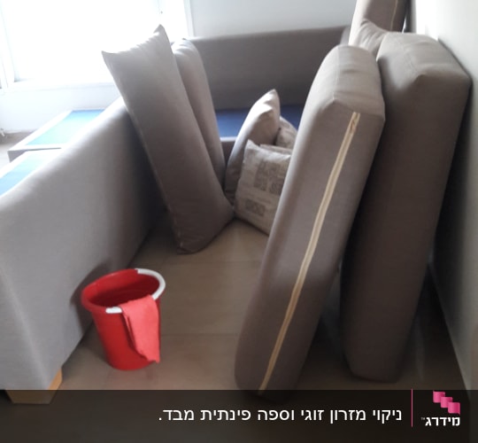 כריות ספה מונחות על הרצפה עם דלי אדום